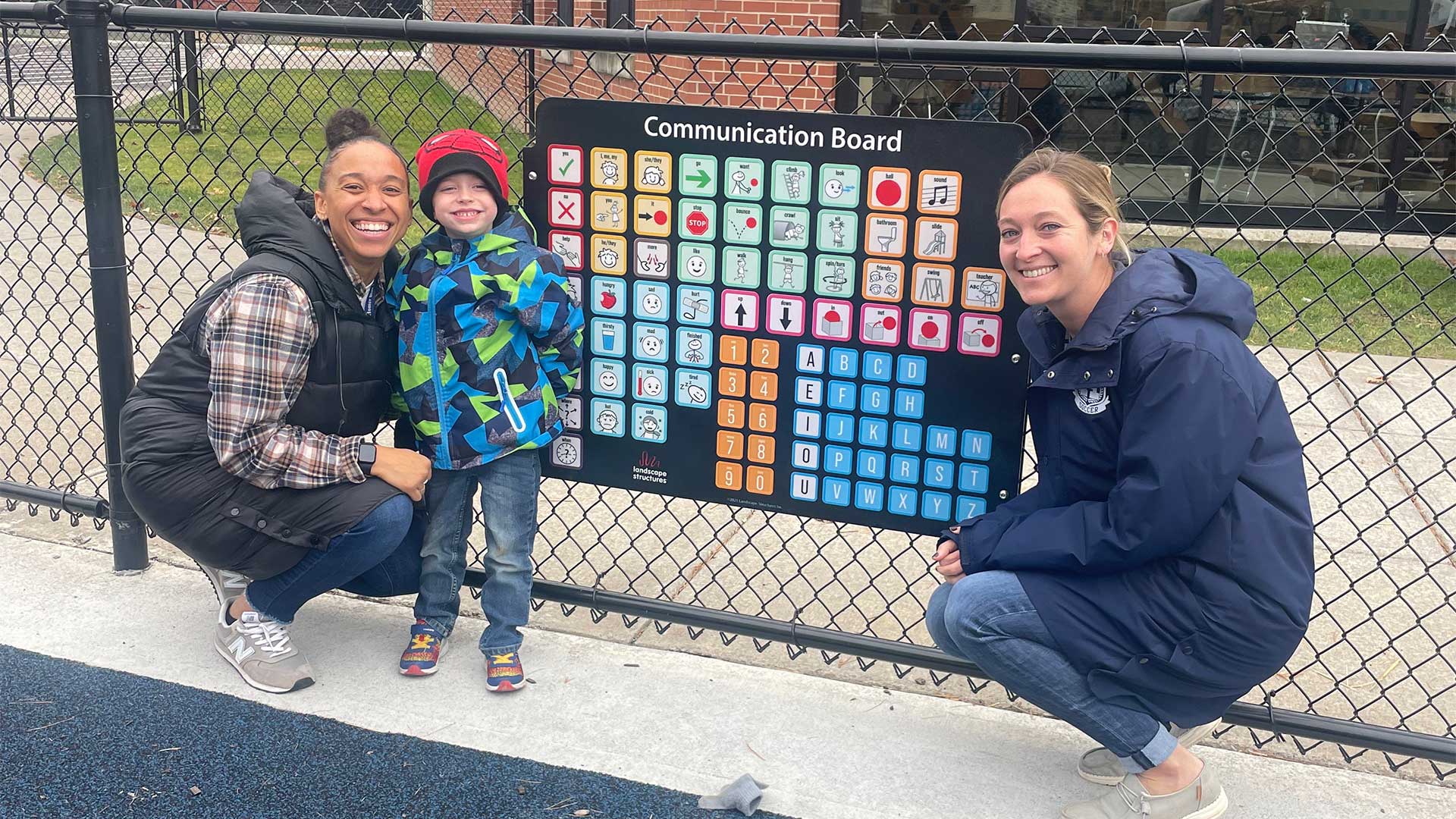 Speech therapist Rachel Parker (right) and teacher Lindsey Kearney (left), both members of the Homer Teachers Association, pose with a student in front one of the district’s new communication boards. Parker helped bring three communication boards to Homer Central School District. 