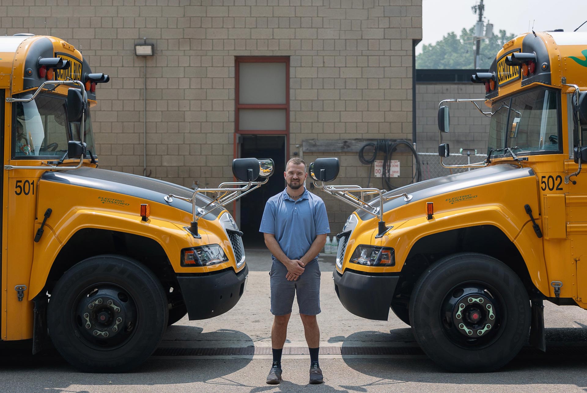 Shaun Keturi, day-to-day operations manager for Ithaca City School District’s transportation department and a member of the Ithaca City School District’s Employees Association, with two of the district’s electric buses. Currently, inadequate power infrastructure in Ithaca has created excessively long charging times for the buses. 