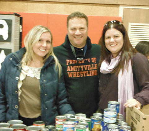 Amityville Teachers Association President Bob Claps and members Christine Gambella, left, and Kristina Komsic help pass out donations of canned food items to help victims of Superstorm Sandy. Community members were also treated to music and a movie.