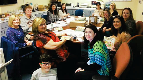 Half Hollow Hills TA elementary teacher volunteers, and a young helper, assemble welcome packages for incoming kindergartners.