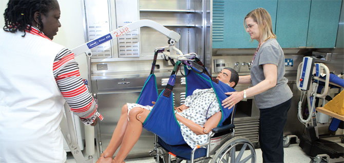 Supervising nurse Michele Scott-Robertson, left, a member of the Professional Staff Association at Albany County Nursing Home, and Karen Wallace, director of physical therapy, demonstrate how to safely move a patient. Photo by Marty Kerins, Jr. 